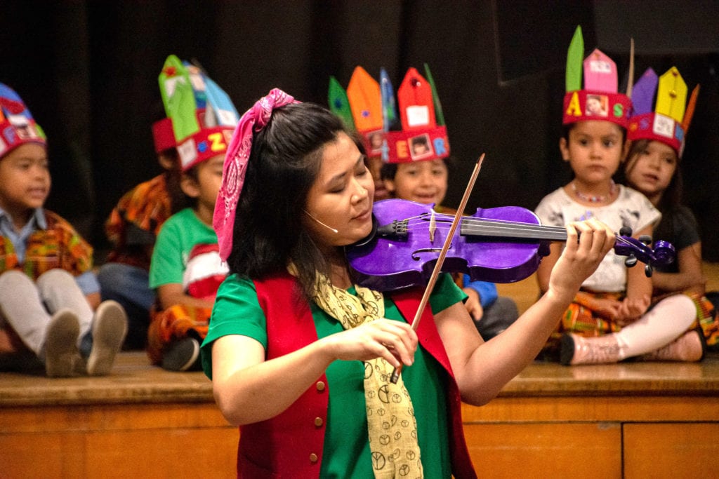 Dream A Word Education artist playing a purple violin for students.