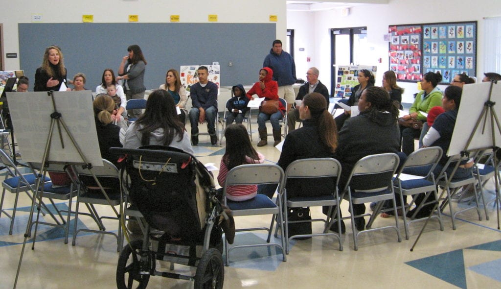 Parents sitting infolding chairs in a circle during a parent workshop.