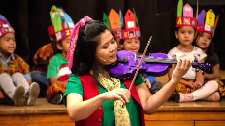 Dream A Word Education artist playing a purple violin for students.