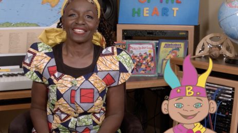 Black woman in colorful clothing and an animated character from a Secrets of the Heart TV video.