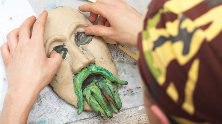 Looking over the shoulder of someone sculpting plasticine face.