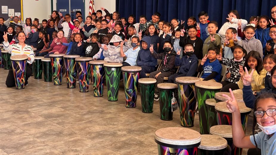 Large group of children in a drum circle.